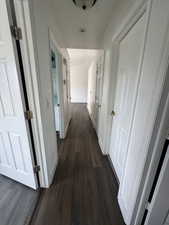Hallway with dark wood-style flooring and baseboards
