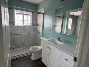 Bathroom with a marble finish shower, vanity, dark wood-type flooring, and healthy amount of natural light