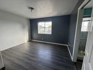 Unfurnished room with dark wood-style floors and a textured ceiling