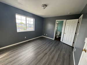 Unfurnished bedroom featuring dark wood finished floors, a textured ceiling, and ensuite bath