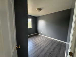 Empty room with wood finished floors and a textured ceiling