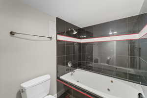 Primary full bath with a combined bath / shower with jetted tub and toilet