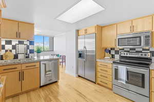 Kitchen with tasteful backsplash, stainless steel appliances, and light brown cabinets