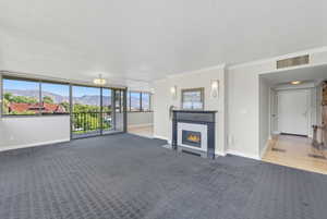 Living room featuring a mountain view, a fireplace with flush hearth, ornamental molding, carpet floors, and a textured ceiling