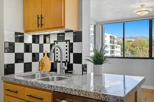 Kitchen featuring backsplash, brown cabinets, a textured ceiling, granite counters,  and a mountain view