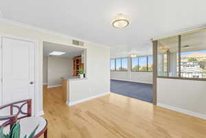 Semi-formal dining room featuring light wood-style flooring and ornamental molding