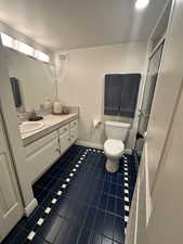 Bathroom with dark tile patterned floors, vanity, and a shower stall