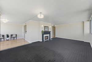 Unfurnished living room with a tiled fireplace, dark carpet, a textured ceiling, and crown molding