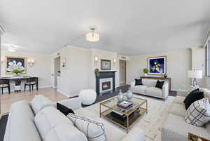 Living room with crown molding, a fireplace with flush hearth, and wood finished floors