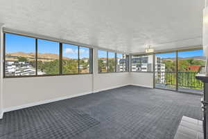 Unfurnished sunroom featuring a mountain view, carpet, and a textured ceiling