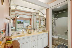 Bathroom featuring shower / bath combo with shower curtain, double vanity, and a ceiling fan