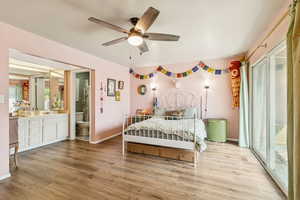 Bedroom featuring light wood-type flooring, access to exterior, a ceiling fan, and ensuite bathroom