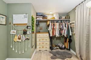 Walk in closet with light wood-style flooring