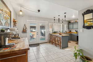 Kitchen featuring french doors, a breakfast bar, decorative light fixtures, gray cabinets, and butcher block counters