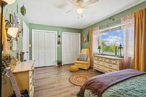 Bedroom with two closets, light wood-style floors, and a ceiling fan