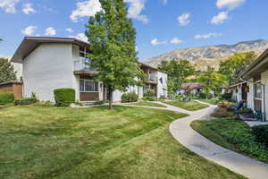 Surrounding community with a balcony, a lawn, a residential view, and a mountain view