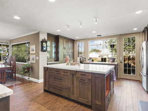 Sun-filled gourmet kitchen featuring high-end Thermador and Bosch appliances, including a double oven with a combi steam option. A large center island and open layout make it ideal for entertaining—stained wood cabinets, tile floors, and recessed lighti