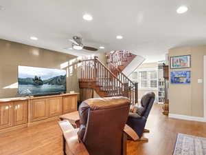 Living room featuring recessed lighting, solid oak floors, stairs, and ceiling fan