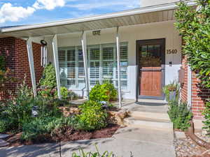 Entrance to property with covered porch and brick siding