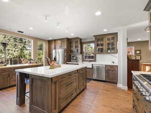 Sun-filled gourmet kitchen featuring high-end Thermador and Bosch appliances, including a double oven with a combi steam option. A large center island and open layout make it ideal for entertaining—stained wood cabinets, tile floors, and recessed lighti