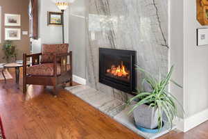 Living room includes a beautiful fireplace surrounded by a marble slab and solid oak flooring.