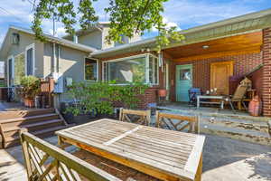 Rear view of house with a covered patio, outdoor dining area, stucco siding, and brick siding