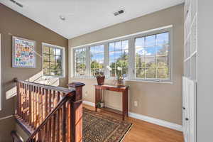 Sunny sitting area to enjoy your favorite morning beverage, featuring an upstairs landing, solid oak floors, a vaulted ceiling, and recessed lighting.