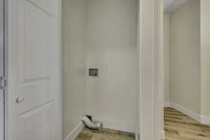 Washroom with light wood finished floors and washer hookup