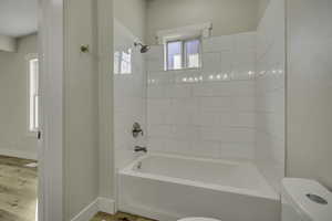 Bathroom with washtub / shower combination and light wood finished floors