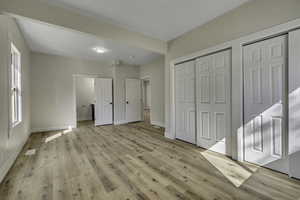 Unfurnished bedroom with multiple closets, light wood finished floors, and connected bathroom