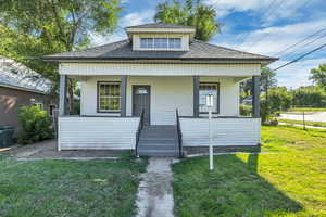 Bungalow-style house featuring a shingled roof, a front yard, and covered porch