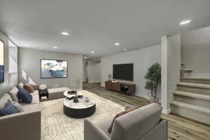 Living area featuring stairs, light wood finished floors, recessed lighting, and a textured ceiling