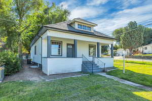 Bungalow featuring roof with shingles, a front yard, and a porch