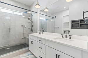 Bathroom with healthy amount of natural light, a shower stall, and double vanity