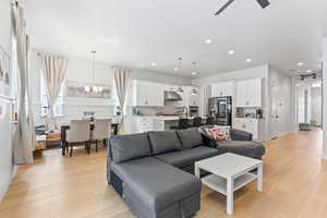 Living room featuring light wood finished floors, a chandelier, and recessed lighting