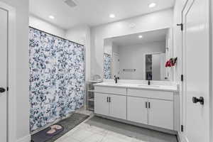 Bathroom with double vanity, a shower with shower curtain, and recessed lighting