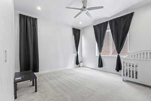 Unfurnished bedroom featuring light colored carpet, a crib, a ceiling fan, and recessed lighting