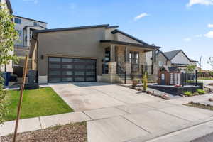 Modern home with stone siding, a porch, and driveway