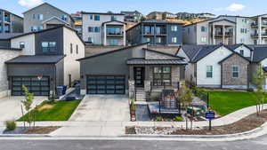View of front of property featuring driveway, stone siding, a front yard, and covered porch