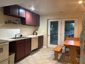 Kitchen featuring light countertops, white appliances, light tile patterned floors, and dark brown cabinets