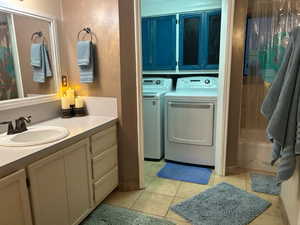 Full bath featuring washer and clothes dryer, vanity, light tile patterned floors, and shower / bath combo