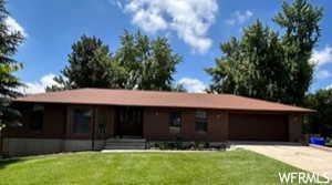 Single story home with driveway, a front yard, covered porch, and a garage