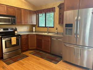 Kitchen featuring stainless steel appliances, light countertops, light wood-style floors, and a textured ceiling