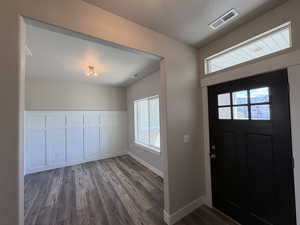 Foyer entrance with a decorative wall, healthy amount of natural light, a wainscoted wall, and wood finished floors