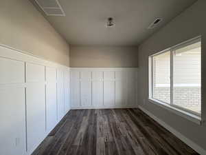 Unfurnished room with dark wood finished floors, a decorative wall, and a wainscoted wall