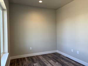 Empty room with dark wood-style flooring and recessed lighting