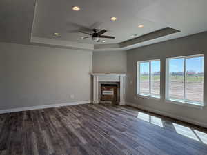 Unfurnished living room featuring a raised ceiling, recessed lighting, and dark wood-style floors