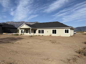 Rear view of house with a mountain view, stucco siding, and roof with shingles