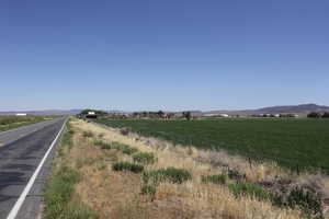 View of asphalt street featuring a view of rural / pastoral area and a mountain view