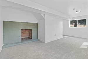 Additional living space with a brick fireplace and carpet floors